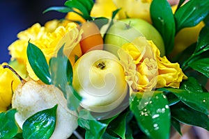 Beautiful handmade bouquet consisting of apples, lemons, kumquats and yellow roses with water drops close-up