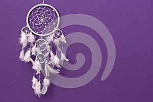 Beautiful handmade dream catcher on purple wall. Space for text
