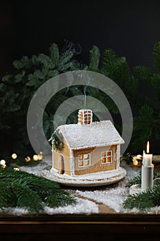 Beautiful handmade gingerbread house with smoke from camino for Christmas and New Year, dark backround, selective focus