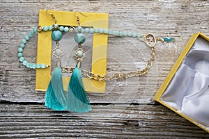 Beautiful handmade  turquoise  jewelry with natural gems in yellow box around old style wooden background. close up. fashion