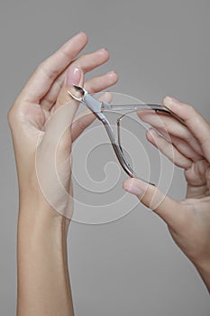 Beautiful hands of a woman with a manicure hold a tool for processing nails. On a gray background