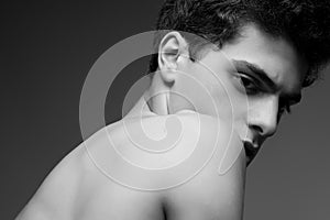 Beautiful handsome muscular male model posing over gray background. Healthy skin. Vogue style. Close up. Copy-space. Black and