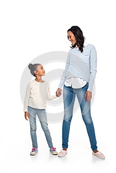 beautiful happy african american mother and daughter holding hands and smiling each other