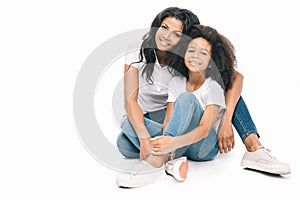 beautiful happy african american mother and daughter sitting together and smiling at camera