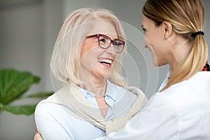 Beautiful happy aged woman embracing young adult daughter and la