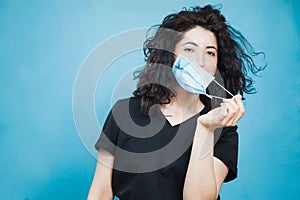 Beautiful happy black haired woman taking off medical antiviral mask.