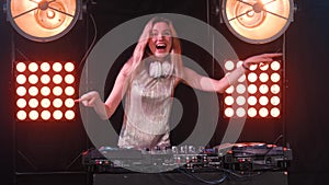 Beautiful happy blonde DJ girl on decks the party