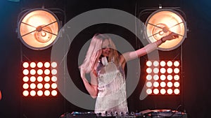 Beautiful happy blonde DJ girl on decks the party