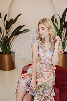 Beautiful happy blonde girl with a shy smile in a summer dress with a floral print. Soft selective focus