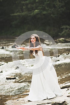 Beautiful happy bride outdoors in a forest with rocks. Wedding perfect day