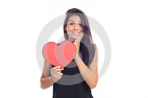 Beautiful happy brunette woman holding and showing a big red heart