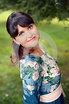 Beautiful happy brunette woman in the park on a warm summer day