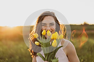 Beautiful happy brunette women holding flowers at sunset