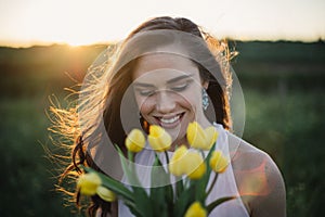 Beautiful happy brunette women holding flowers at sunset