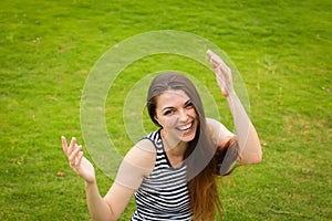 Beautiful happy brunette young woman smiling on green grass outside