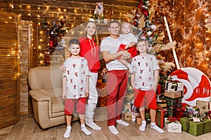 Beautiful happy Caucasoid family of five in white and red clothes for Christmas. children and parents