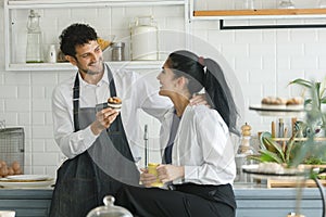 Beautiful happy cheerful caucasian couple wear apron in kitchen and dessert breakfast morning with love emotion. man and women
