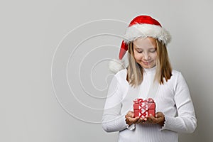 Beautiful happy child girl Sante looking at Xmas gift. Young cute girl Christmas portrait photo