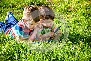 Beautiful happy children, boy brothers, exploring nature with magnifying glass, summertime