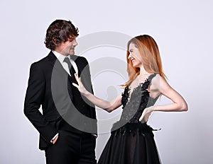 Beautiful happy couple flirting and speaking on blue background in evening fashion clothing. Redheaded hairstyle laughing girl and