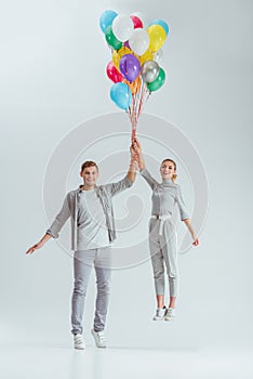 beautiful happy couple jumping with bundle of colorful balloons