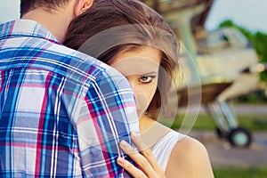 Beautiful happy couple in love standing near the old planes hugging the girl looks over the shoulder of the guy