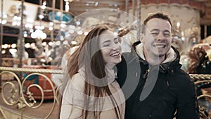 A beautiful happy couple in a lunapark hugs. Against the background of merry-go-rounds. Close-up.