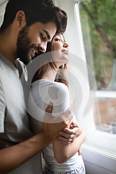 Beautiful happy couple of young lovers are hugging indoors at home, with love and tenderness