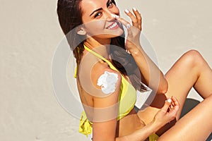 Beautiful happy cute woman applying suntan cream to her nose with beach  background. Skin care. Cosmetics