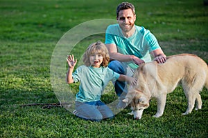 Beautiful happy family is having fun with dog husky. Happy father and his son playing with dog in park.