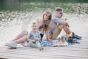 Beautiful happy family having picnic near lake
