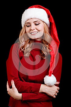Beautiful happy festive girl in a santa cap on a black background. Christmas costume concept.