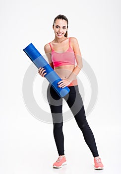 Beautiful happy fitness woman standing and holding yoga mat