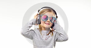 Beautiful happy fun young child blond girl with sunglasses listening to music using headphones and dancing.Person action