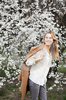 Beautiful happy girl in blossom garden on a spring day