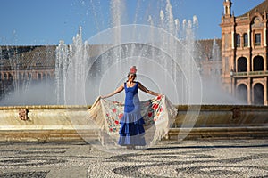 A beautiful happy girl with flamenco dress in front of the fountain photo