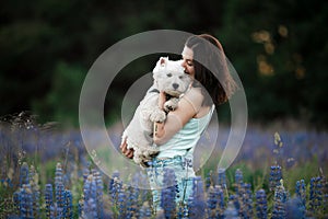 Beautiful and happy girl hugging little west highland white terrier. Big true love to home beloved pets