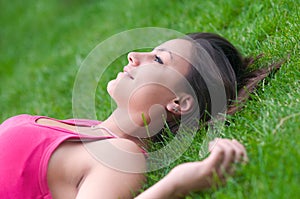Beautiful happy girl lying on the green grass