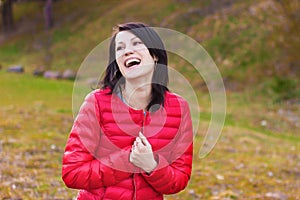 Beautiful, happy girl with perky smile in red jacket is in the forest