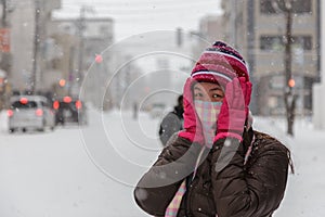 Beautiful and happy girl with scarf cover mouth in winter snowy day outdoors