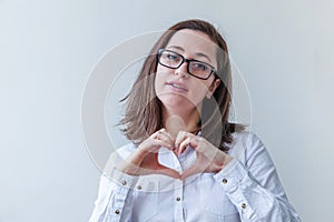 Beautiful happy girl smiling. Beauty simple portrait young woman in eyeglasses showing heart sign with hands isolated on white