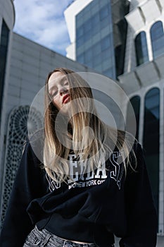 Beautiful happy girl in a sports hoodie in the city. Portrait. Fashion