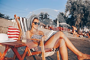 Smiling girl reading a book while sitting on deck chair