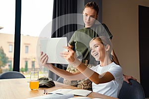 Beautiful happy girl taking selfie with her mather on tablet computer