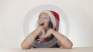 Beautiful happy girl teenager in a Santa Claus hat look and emotionally expresses a surprise on white background