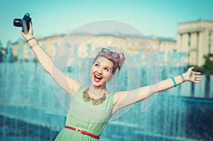 Beautiful happy girl in vintage clothing with retro camera