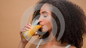 Beautiful happy healthy African American woman ethnic girl female model with curly hair drinking fresh orange juice