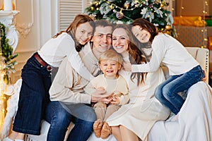 Beautiful happy large family on the couch by the Christmas tree.