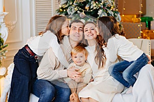 Beautiful happy large family on the couch by the Christmas tree.