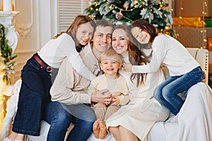 Beautiful happy large family on the couch by the Christmas tree.